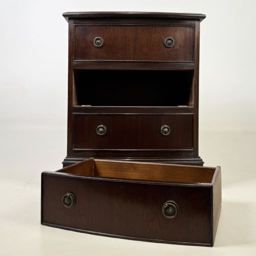 fig 8. A dark mahogany small chest of three drawers featuring brass ring pull handles and bracket feet.