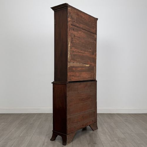 fig 4. A tall dark mahogany bookcase featuring a serpentine front profile, upper astragal glazed double doors, and a lower double-door cupboard.