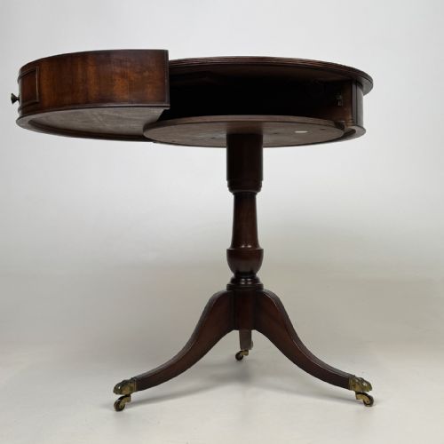 fig 5. An Edwardian mahogany drum table featuring a circular top with a frieze drawer, supported by a turned pedestal and tripod swept legs on brass claw castors.