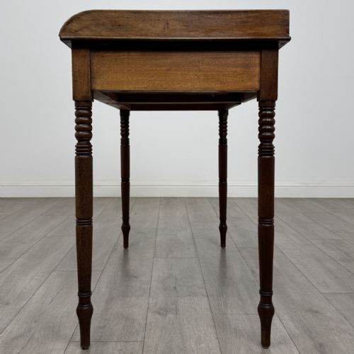 fig 2. An antique Georgian mahogany writing table featuring a raised gallery edge, two frieze drawers with brass circular handles, and slender turned legs.