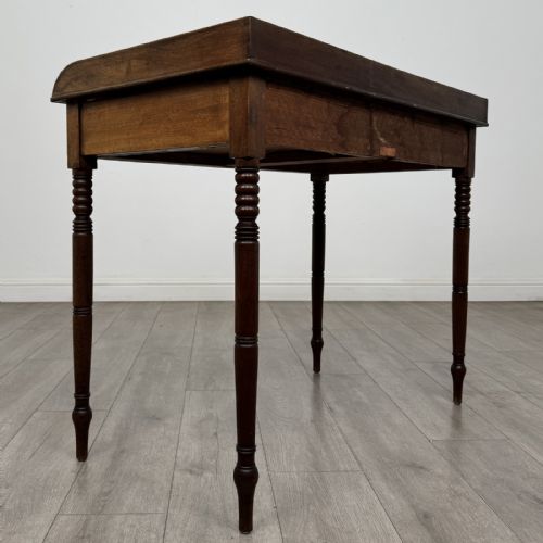 fig 3. An antique Georgian mahogany writing table featuring a raised gallery edge, two frieze drawers with brass circular handles, and slender turned legs.