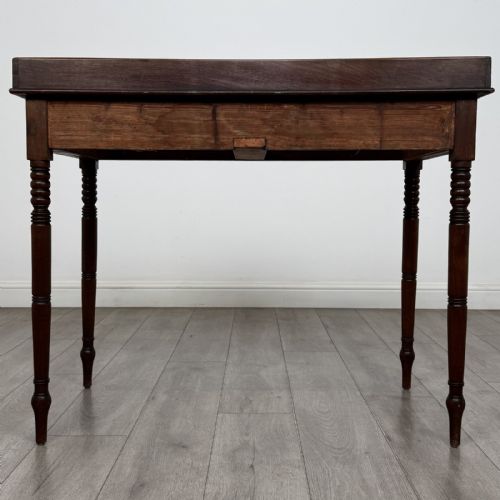 fig 4. An antique Georgian mahogany writing table featuring a raised gallery edge, two frieze drawers with brass circular handles, and slender turned legs.
