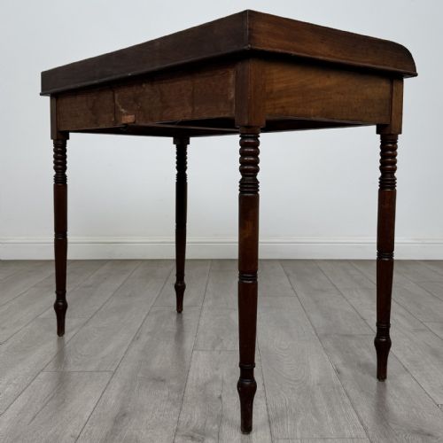 fig 5. An antique Georgian mahogany writing table featuring a raised gallery edge, two frieze drawers with brass circular handles, and slender turned legs.