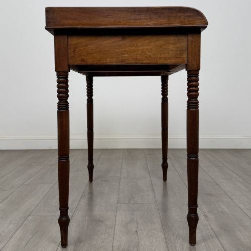 fig 6. An antique Georgian mahogany writing table featuring a raised gallery edge, two frieze drawers with brass circular handles, and slender turned legs.