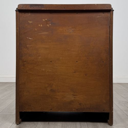 fig 4. A dark brown oak chest of drawers with geometric panel moulding, four horizontal drawers, ornate metal ring handles, and a plinth base.