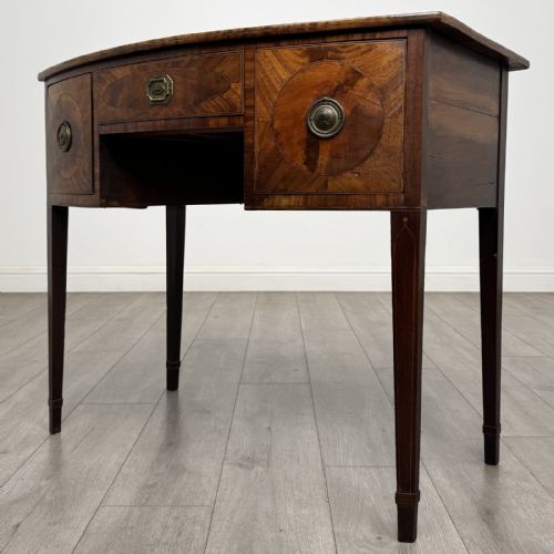 fig 1. An antique Georgian mahogany bow-front side table with flame mahogany inlaid drawers, brass ring handles, and tapered square legs.