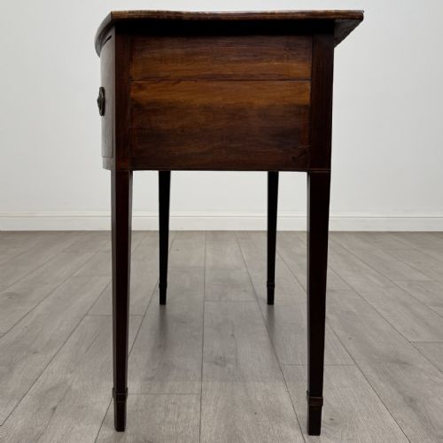fig 2. An antique Georgian mahogany bow-front side table with flame mahogany inlaid drawers, brass ring handles, and tapered square legs.