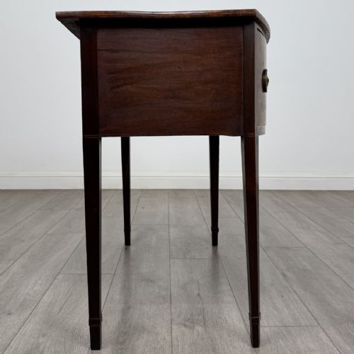 fig 6. An antique Georgian mahogany bow-front side table with flame mahogany inlaid drawers, brass ring handles, and tapered square legs.