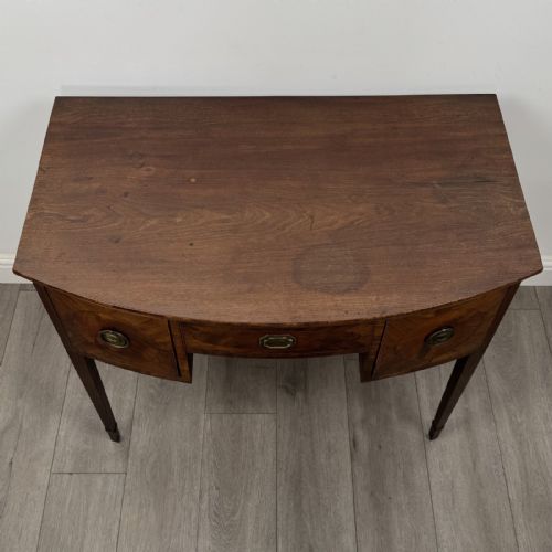 fig 8. An antique Georgian mahogany bow-front side table with flame mahogany inlaid drawers, brass ring handles, and tapered square legs.