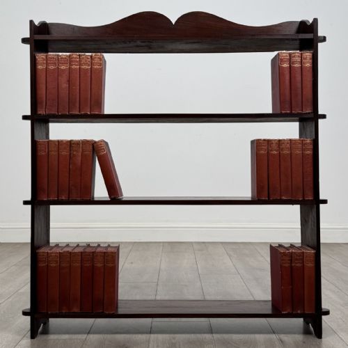 fig 1. A dark mahogany open bookcase featuring four tiered open shelves and a shaped, scalloped raised gallery back.