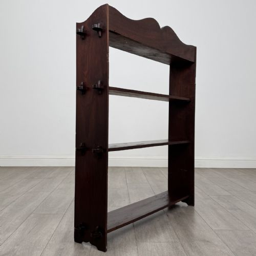 fig 4. A dark mahogany open bookcase featuring four tiered open shelves and a shaped, scalloped raised gallery back.
