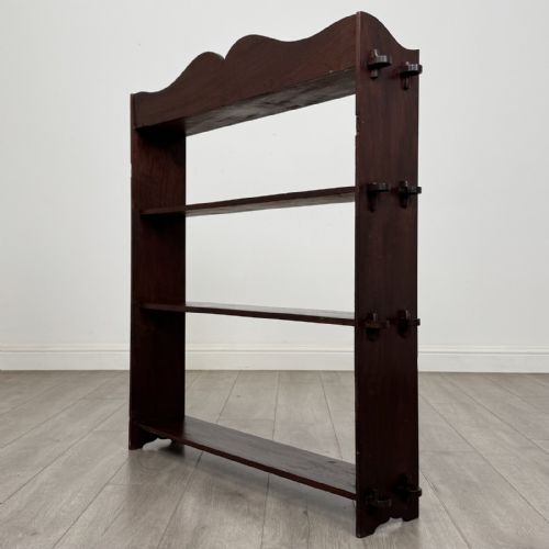 fig 6. A dark mahogany open bookcase featuring four tiered open shelves and a shaped, scalloped raised gallery back.