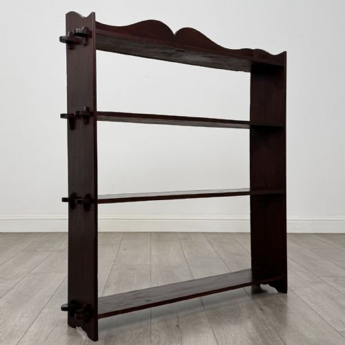 fig 8. A dark mahogany open bookcase featuring four tiered open shelves and a shaped, scalloped raised gallery back.
