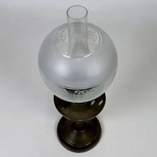 fig 7. An antique Victorian brass oil lamp featuring a circular stepped base, a columnar pedestal supporting a round brass reservoir, a burner assembly, a spherical etched frosted glass shade, and a clear glass chimney.