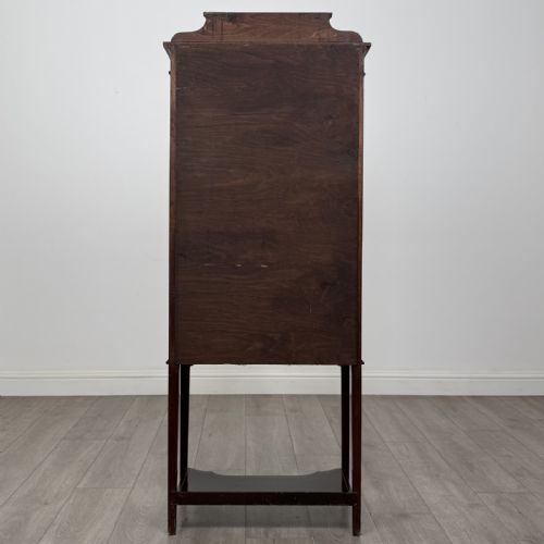 fig 5. An Edwardian mahogany display cabinet featuring a painted inlaid floral frieze, single astragal glazed door, fabric-lined interior shelves, and tapered legs with a lower undertier.