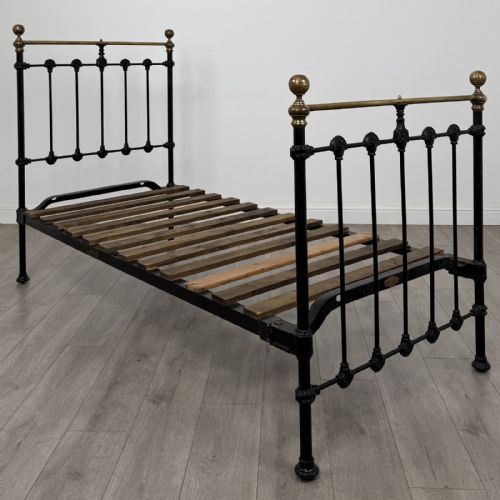 fig 1. A Victorian single bed frame constructed from black cast iron spindles and topped with a brass top rail and ball finials.