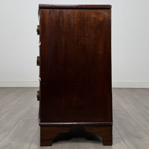 fig 2. A Georgian mahogany bow front chest of drawers featuring three horizontal drawers with brass ring handles and bracket feet.