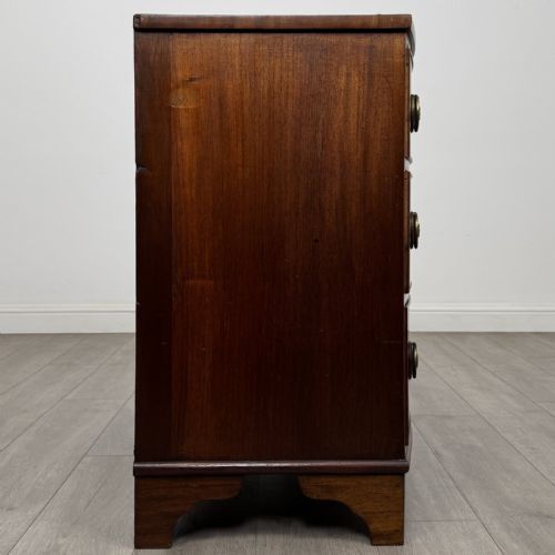 fig 6. A Georgian mahogany bow front chest of drawers featuring three horizontal drawers with brass ring handles and bracket feet.