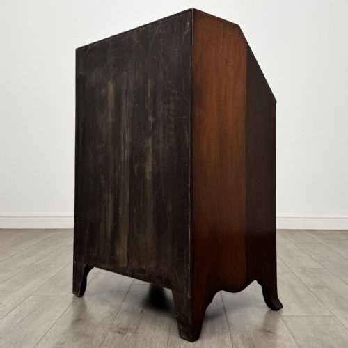 fig 4. A small Georgian style dark mahogany writing bureau featuring an inlaid oval motif on the slant-front lid and four drawers with brass handles.