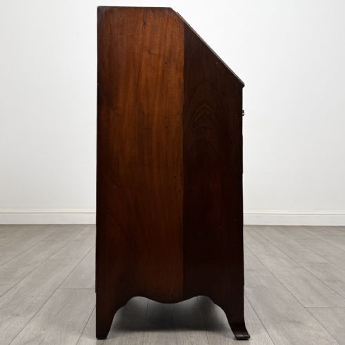 fig 5. A small Georgian style dark mahogany writing bureau featuring an inlaid oval motif on the slant-front lid and four drawers with brass handles.