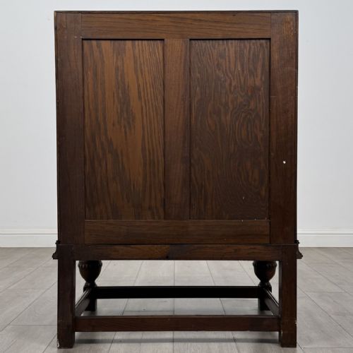 fig 5. An antique dark oak fall-front writing bureau featuring a carved oval motif on the sloping lid, two lower drawers with wooden handles, and bulbous turned front legs on a stretcher base.