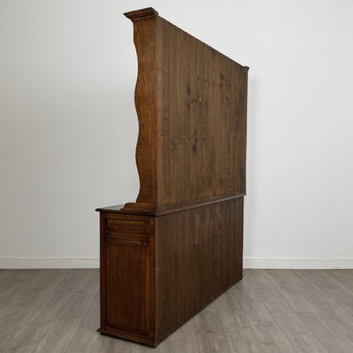 fig 4. A vintage dark oak Welsh dresser featuring an upper open shelving rack with a shaped top apron and a lower storage unit with three drawers and three panelled cupboard doors.
