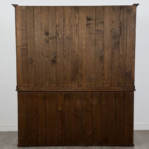 fig 5. A vintage dark oak Welsh dresser featuring an upper open shelving rack with a shaped top apron and a lower storage unit with three drawers and three panelled cupboard doors.