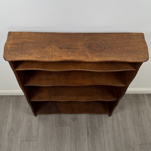 fig 8. An antique 20th-century solid oak open bookcase featuring four fixed shelves and gently shaped side panels.