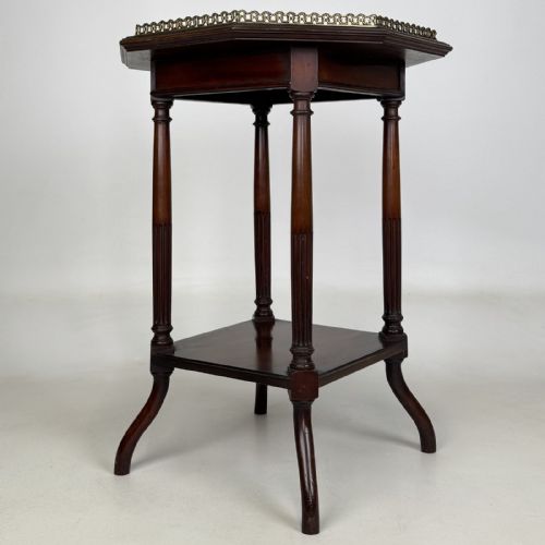 fig 1. An octagonal dark mahogany side table featuring a pierced brass gallery top, turned fluted columns, a lower tier shelf, and splayed legs.