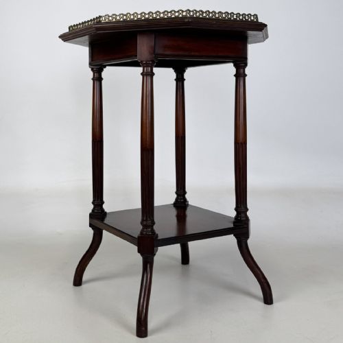 fig 7. An octagonal dark mahogany side table featuring a pierced brass gallery top, turned fluted columns, a lower tier shelf, and splayed legs.