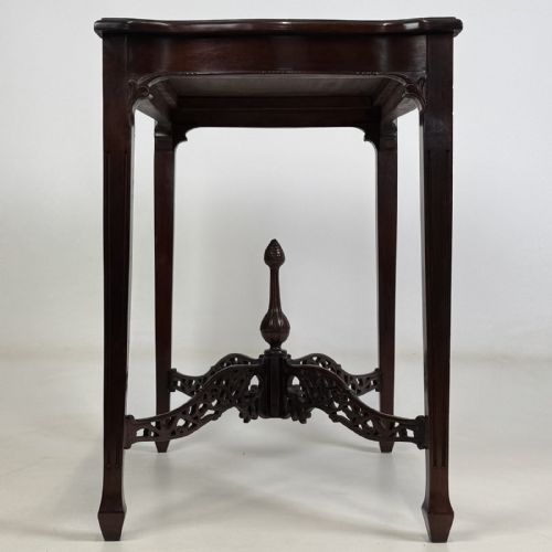 fig 2. An Edwardian mahogany side table with four square tapered legs, a carved fretwork X-stretcher, and a central turned finial.