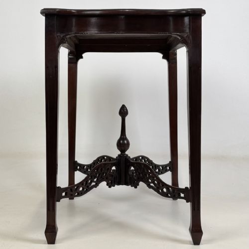 fig 6. An Edwardian mahogany side table with four square tapered legs, a carved fretwork X-stretcher, and a central turned finial.