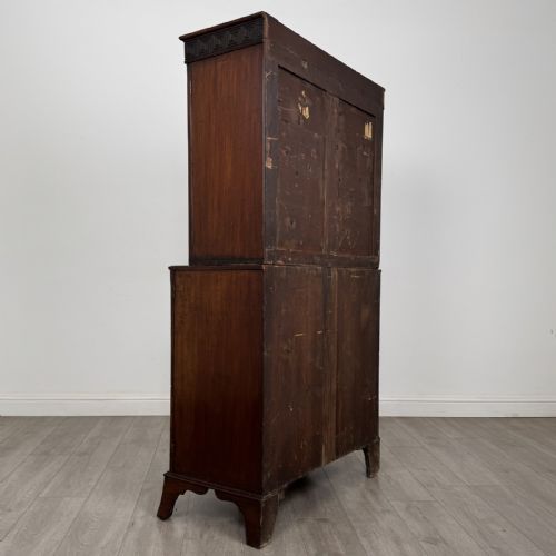fig 3. An eighteenth-century Georgian mahogany glazed bookcase featuring an upper cabinet with glass doors and a lower cabinet with carved doors, lion mask handles, and Greek key frieze details.