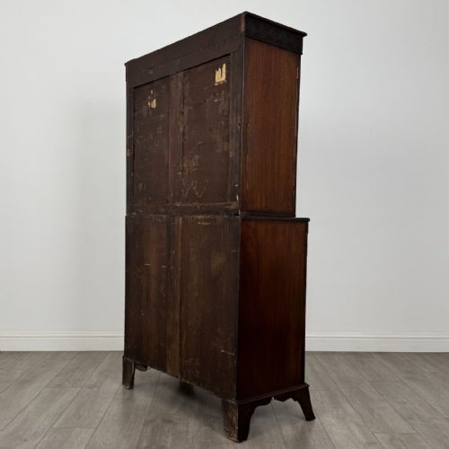 fig 5. An eighteenth-century Georgian mahogany glazed bookcase featuring an upper cabinet with glass doors and a lower cabinet with carved doors, lion mask handles, and Greek key frieze details.