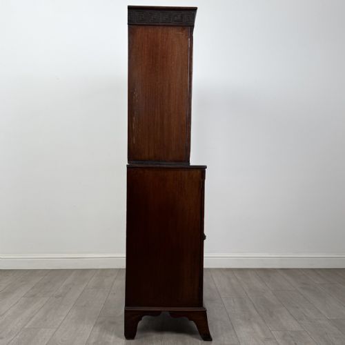 fig 6. An eighteenth-century Georgian mahogany glazed bookcase featuring an upper cabinet with glass doors and a lower cabinet with carved doors, lion mask handles, and Greek key frieze details.