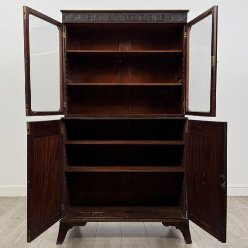 fig 8. An eighteenth-century Georgian mahogany glazed bookcase featuring an upper cabinet with glass doors and a lower cabinet with carved doors, lion mask handles, and Greek key frieze details.
