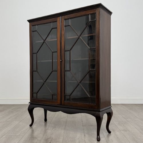 fig 1. An Edwardian dark mahogany display cabinet featuring twin astragal glazed doors and shaped cabriole legs.