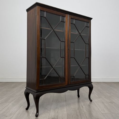 fig 7. An Edwardian dark mahogany display cabinet featuring twin astragal glazed doors and shaped cabriole legs.