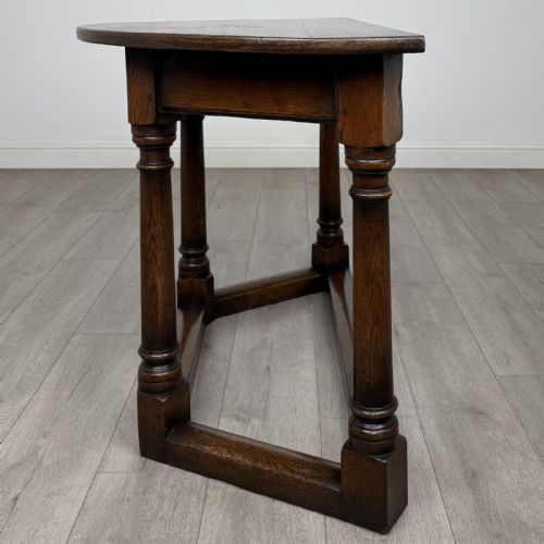 fig 2. A dark oak demi-lune side table featuring turned legs and a low perimeter stretcher base.