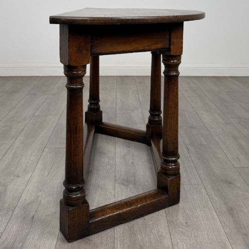 fig 4. A dark oak demi-lune side table featuring turned legs and a low perimeter stretcher base.