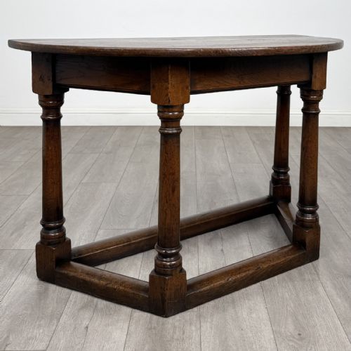fig 5. A dark oak demi-lune side table featuring turned legs and a low perimeter stretcher base.