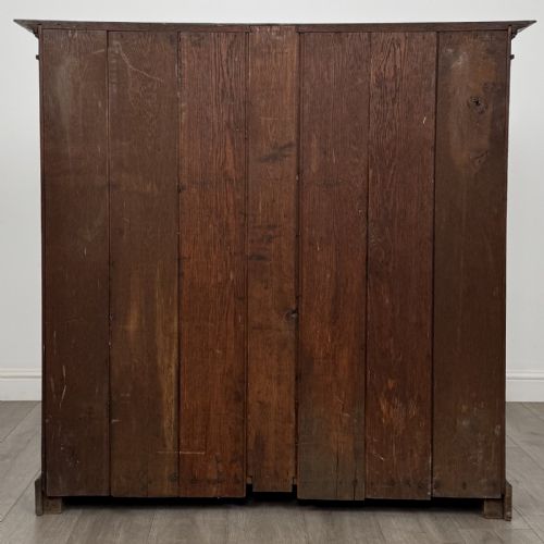 fig 4. An antique dark oak open bookcase featuring four shelf sections, a dentil carved cornice at the top, and a solid base.