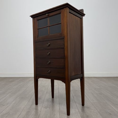 fig 1. A tall, narrow Edwardian mahogany cabinet featuring a top four-pane glazed compartment above four stacked drawers, resting on slim tapered legs.