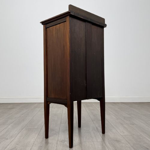 fig 3. A tall, narrow Edwardian mahogany cabinet featuring a top four-pane glazed compartment above four stacked drawers, resting on slim tapered legs.