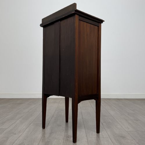 fig 5. A tall, narrow Edwardian mahogany cabinet featuring a top four-pane glazed compartment above four stacked drawers, resting on slim tapered legs.