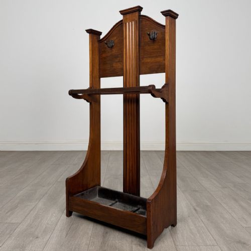 fig 1. An Edwardian walnut hall stand featuring central fluted wood paneling, two metal hanging hooks, a stick retention bar, and a lower drip tray.