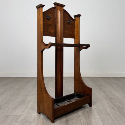 fig 7. An Edwardian walnut hall stand featuring central fluted wood paneling, two metal hanging hooks, a stick retention bar, and a lower drip tray.