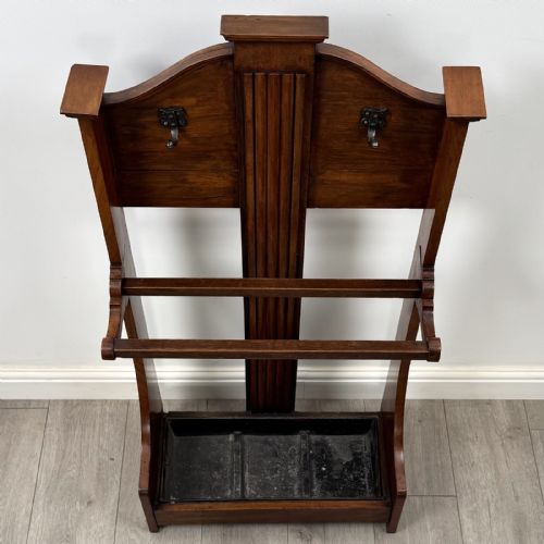 fig 8. An Edwardian walnut hall stand featuring central fluted wood paneling, two metal hanging hooks, a stick retention bar, and a lower drip tray.