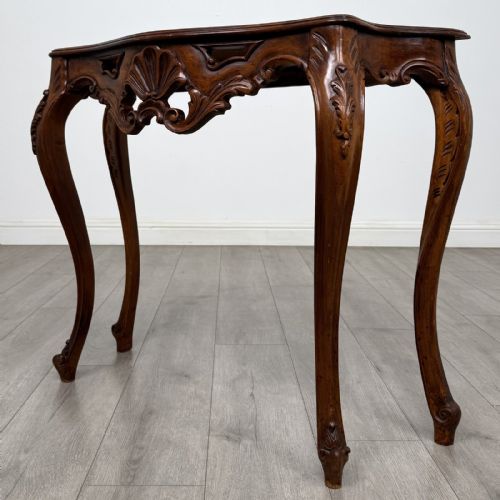 fig 1. A carved mahogany French style side table featuring exaggerated cabriole legs, a shell motif apron, and a serpentine tabletop.