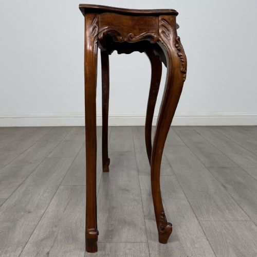 fig 6. A carved mahogany French style side table featuring exaggerated cabriole legs, a shell motif apron, and a serpentine tabletop.